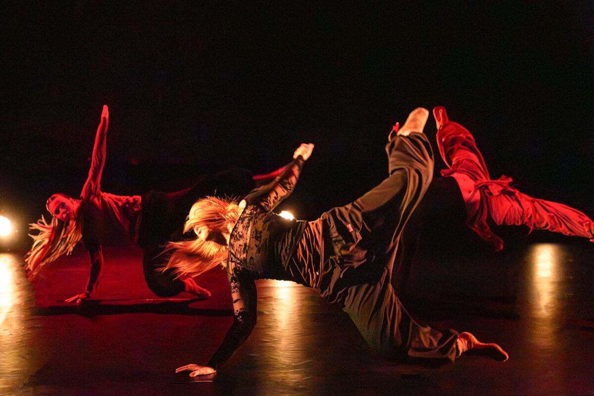 a contemporary dancer on the floor kicking a leg in the air